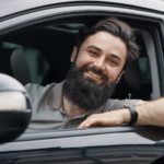 Young man smiling while driving a car